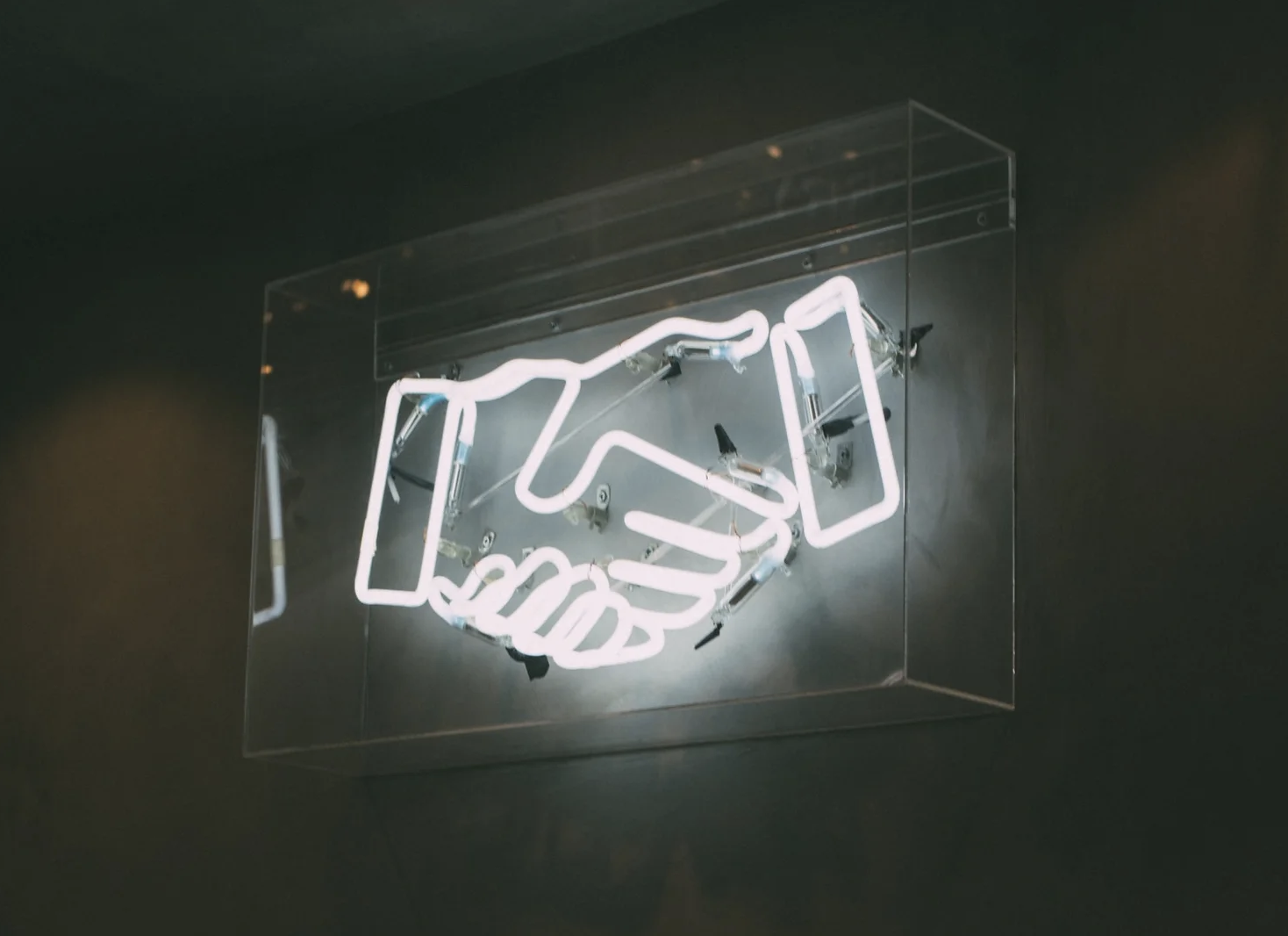 Neon sign of two hands shaking